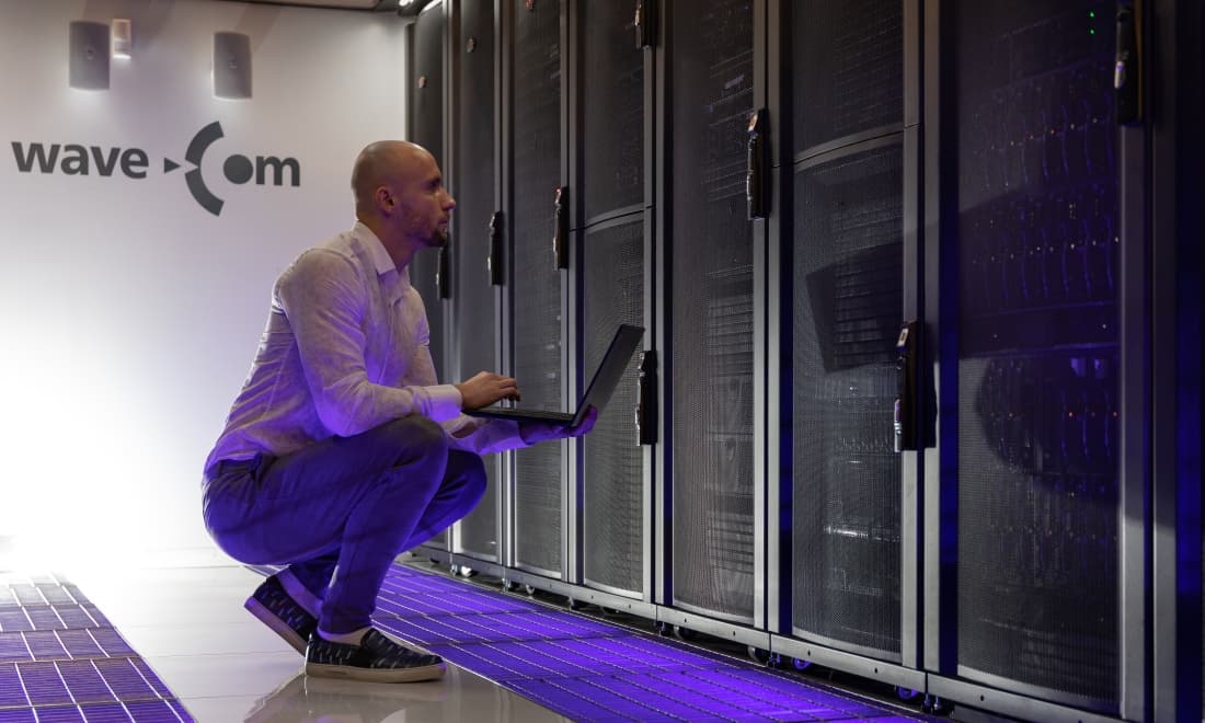 WaveCom engineer working on a laptop in front of server cabinets